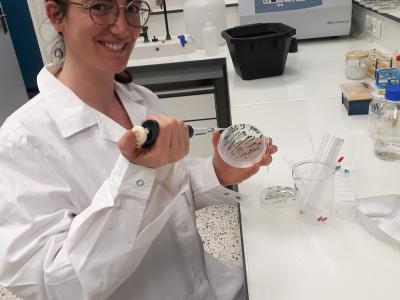 Photo portrait d’Hélène Launay devant sa paillaisse avec une pipette en main.